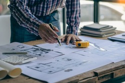 Close-up of a man working on a project sketching architects on blueprints at a construction site. Architect, engineer concept in desk construction project banner
close-up of drawing plans with archite