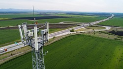Aerial shot of telecommunication tower with highway on the back. Telecom tower antennas and satellite transmits the signals of cellular 5g 4g 3g lte mobile signals to the consumers and smartphones.