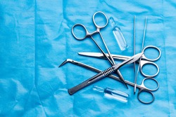 stack of surgical equipment at surgery desk. medical tools such scissors, scalpel, forceps, tweezers over blue background. surgery concept.