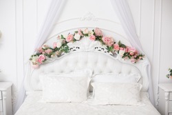 White beautiful bedhead decorated with flowers. Royal bedroom in white color