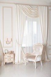 Elegant arm-chair with near a window. Luxury interior in white colors. Armchair with velvet upholstery