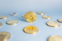 Monero coin standing centrally placed among bunch of cryptocurrency coins on blue background. Banner with golden XMR crypto token. Close-up, soft focus.