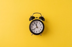 Time management, punctuality, business metaphors. White vintage alarm clock with nine ten on yellow background, flat lay top view, copy space