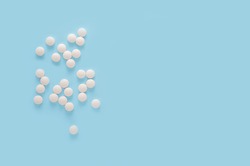 white round pills, pills isolated on blue background. Scattered medicine pills. Healthcare, medical and pharmaceutical concept. top view. copy space
