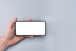 Mockup cell phone. male hand holding phone horizontally with blank white screen. Mockup phone horizontal. human left hand holding black horizontal mobile phone
