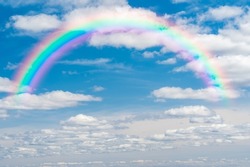 beautiful sky with colorful rainbow. Stunning blue sky panoramic rainbow big fluffy clouds with a giant arcing rainbow against beautiful summer time blue sky with copy space for messages or text