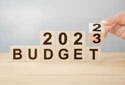 Business concept of planning 2023. Businessman flips wooden cube and changes words BUDGET 2022 to BUDGET 2023. New year business plan concept in 2023. Economy and business.Phrase 2023 BUDGET