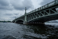 Bridge. A low metal bridge across the river in cloudy weather in gloomy dark colors. St. Petersburg. old bridge