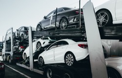 Big car carrier truck of new luxury sport  german cars for batch delivery to dealership . Full load transport truck of new powerful new vehicles. Automotive industry  rent  shipping background.