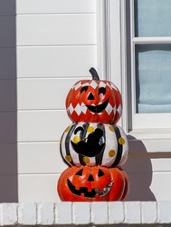 Three color plastic Halloween pumpkins are stacked on top of each other. The middle pumpkin has a hold where the face should be. The bottom pumpkin is orange, middle white and the top one is red. They
