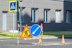 attention, stop, detour, road repair signs installed in the city near a pedestrian crossing near the windows of an industrial building