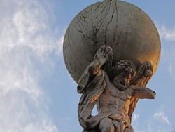 Upwards view to statue of Atlas with blue sky with few clouds in the park