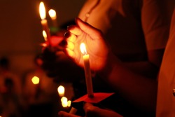 De focused Candlelight with people. Bokeh of light candle,Crowds gather to do candlelight activities. Closeup of people holding candle vigil in darkness expressing and seeking hope.