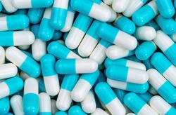Top view pile of blue and white antibiotic capsule pills texture. Pharmaceutical production. Global healthcare. Antibiotics drug resistance. Antimicrobial capsule pills. Pharmaceutical industry.