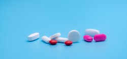Pharmacy banner. White and pink tablets pills on blue background. Round and oval tablets. Painkiller medicine. Acetaminophen and ibuprofen tablets pills. Pharmaceutical industry. Painkiller tablets.