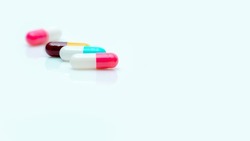 Selective focus on antibiotic capsule pill. Pharmaceutical industry. Prescription drugs. Pharmacy web banner. Pink, blue, yellow, red capsules pill on white background. Antibiotic drug resistance. 