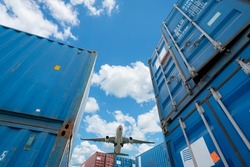 Selective focus on stack of blue container. Airplane flying above logistic container. Air logistics. Cargo and shipping business. Container ship for import and export logistic. Logistic industry. 