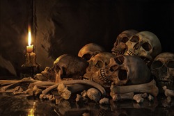 Pile of Skulls and bones on the reflection floor and old dirty wall have Lighting by candlelight / Still Life Image and dim light and adjustment color for background