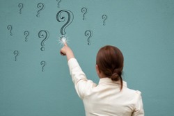 A business women touch question mark on the blue wall, question and answer concept focus on the wall
