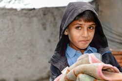 a young cute boy is receiving blanket by a charity relief work 