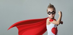 Funny strong child raising hand in success gesture. Little cool boy superhero loves mom, shows heart. Portrait confident kid in costume super hero expresses strength, leadership. banner, copy space.