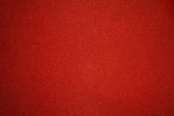 Elegant red canvas background with vignette and small dots. Scarlet backdrop for festive decoration and internet design. texture of sandpaper