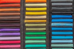 A set of colored pastel crayons for the artist in a foam lodgment, top view