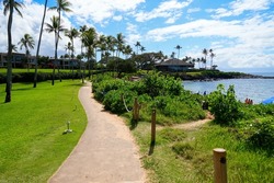 Walking path on the Kapalua Coastal Trail winding between luxury apartment buildings and the beach on Kapalua Bay in West Maui, Hawaii