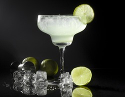 Glass of margarita cocktail on a black background.