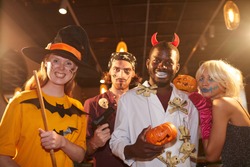 Waist up portrait of adult people wearing Halloween costumes posing as witches and pirates grimacing at camera during party, shot with flash