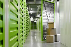 Background image of green self storage facility with opened unit door and cardboard boxes, copy space
