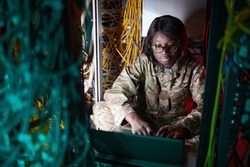 High angle portrait of young African-American woman wearing military uniform while using computer in server room