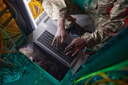 Cropped high angle portrait of young African-American woman wearing military uniform while using computer in server room