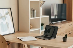 Background image of minimal home office setup with blank laptop on wooden desk in cozy apartment, copy space