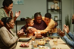 Portrait of smiling African-American man embracing children while celebrating Birthday with big happy family