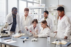 Large group of diverse children wearing lab coats in chemistry class while enjoying science experiments