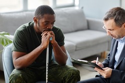 Depressed young adult African American soldier with walking stick treating PTSD with psychotherapy sessions