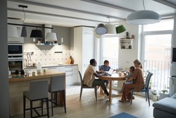 Wide angle home scene of modern multiethnic family at dinner table in kitchen, copy space