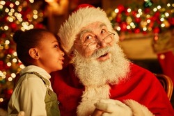Portrait of cute  girl whispering secrets to Santa Claus on Christmas eve