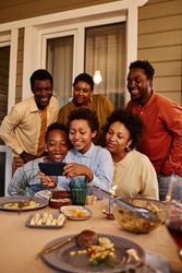 Vertical portrait of happy African American family taking selfie photo at house terrace in evening