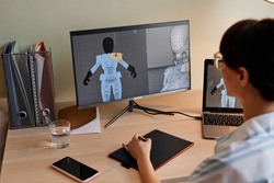 Close up of female designer building digital 3D models for videogame characters at workplace