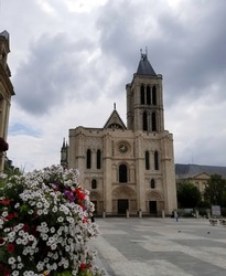 West facade of the Basilica Cathedral of Saint Denis and blooming petunia at foreground, France. Focus on background.