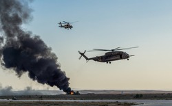 A pair of black hawk helicopters fly by and fire explosive rounds at distant targets in Tel Aviv, Israel.
