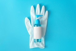 Top down view blue alcohol liquid for medical purpose and Anti coronavirus COVID-19 (Ethanol or ethyl alcohol) in a plastic press pump head blue bottle with blank label on white disposable glove. 