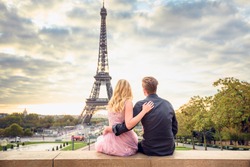 Sunrise in front of the Eiffel tower in Paris. Couple hugging each other and looking at the city from the top of the Trocadero place