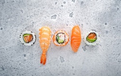 A variety of sushi nigiri and maki with salmon on a stone background. Asian cuisine menu for background