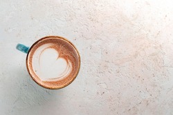 Cocoa mug with a heart pattern on the foam.  Drink with hot chocolate on a stone table, top view and copy space