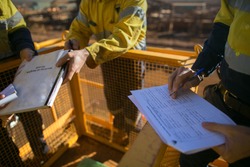 Trained supervisor competent checking reviewing document issued sign approvals of working at height permit JSA risk assessment on site prior to performing high risk work construction site, Australia 