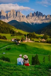 couple viewing the landscape of Santa Maddalena Village in Dolomites Italy, Santa Magdalena village magical Dolomites mountains, Val di Funes valley, Trentino Alto Adige region, South Tyrol, Italy, 