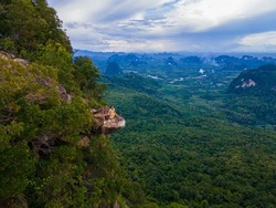 Dragon Crest mountain Krabi Thailand, a Young traveler sits on a rock that overhangs the abyss, with a beautiful landscape. Dragon Crest or Khuan Sai at Khao Ngon Nak Nature Trail in Krabi, Thailand